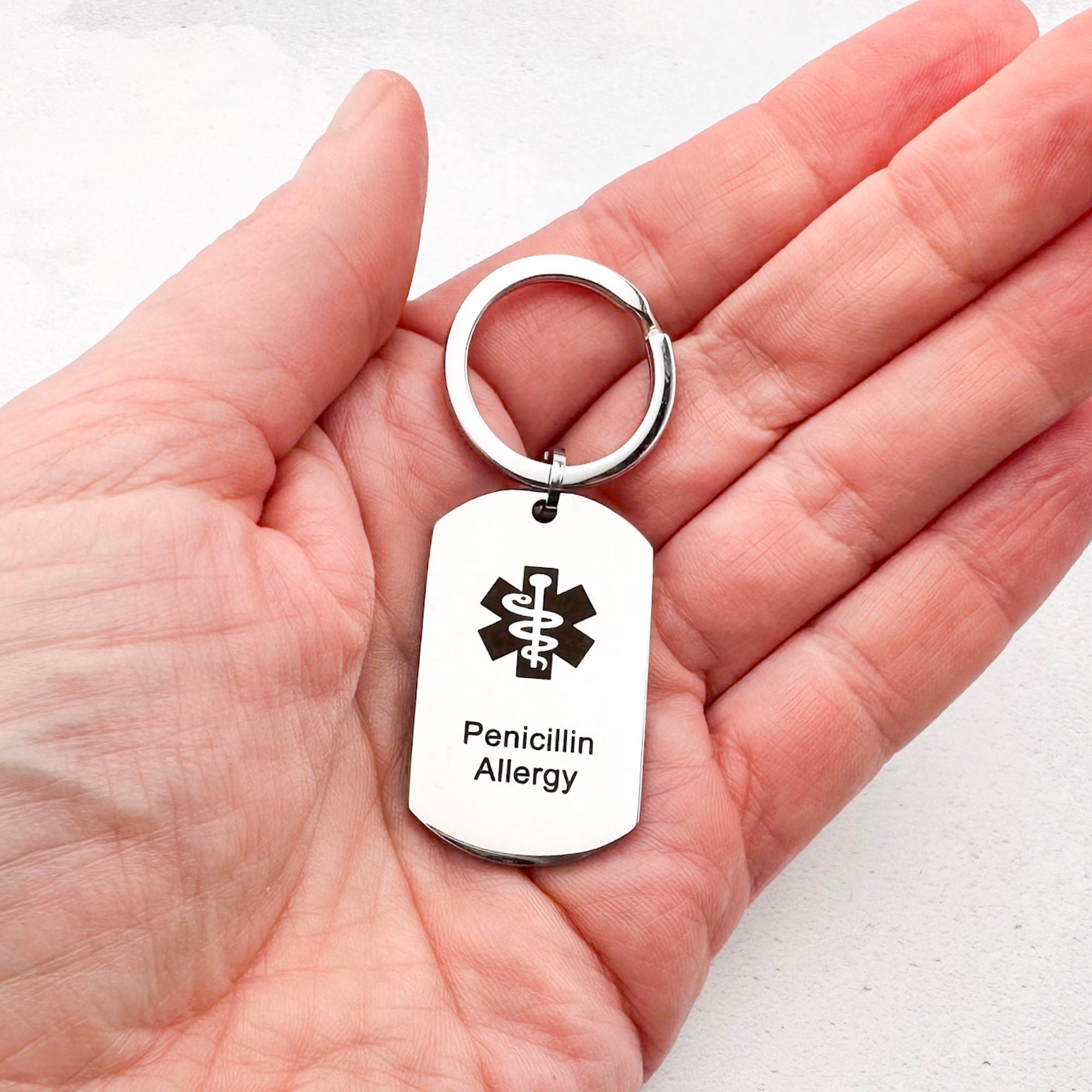 stainless steel penicillin allergy keychain held in hand for scale