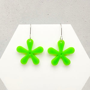 Green flower-shaped earrings on a white card with a gray background