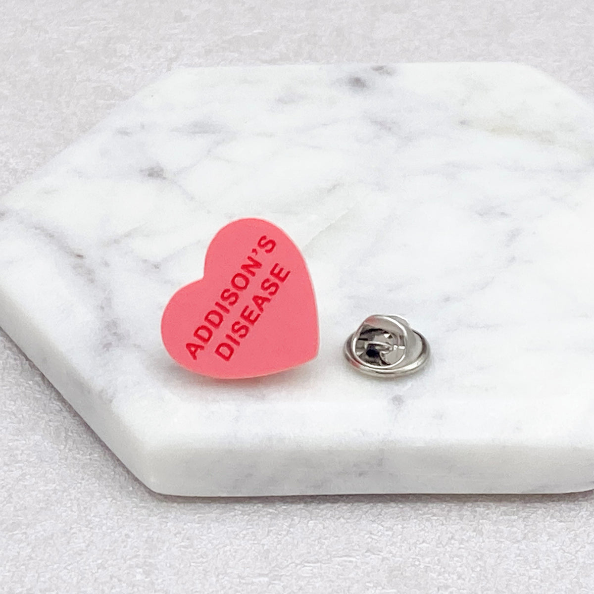 Addison’s disease awareness pin with red lettering on heart-shaped acrylic