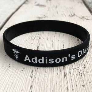 Black wristband with 'Addison's Disease' text on a wooden surface