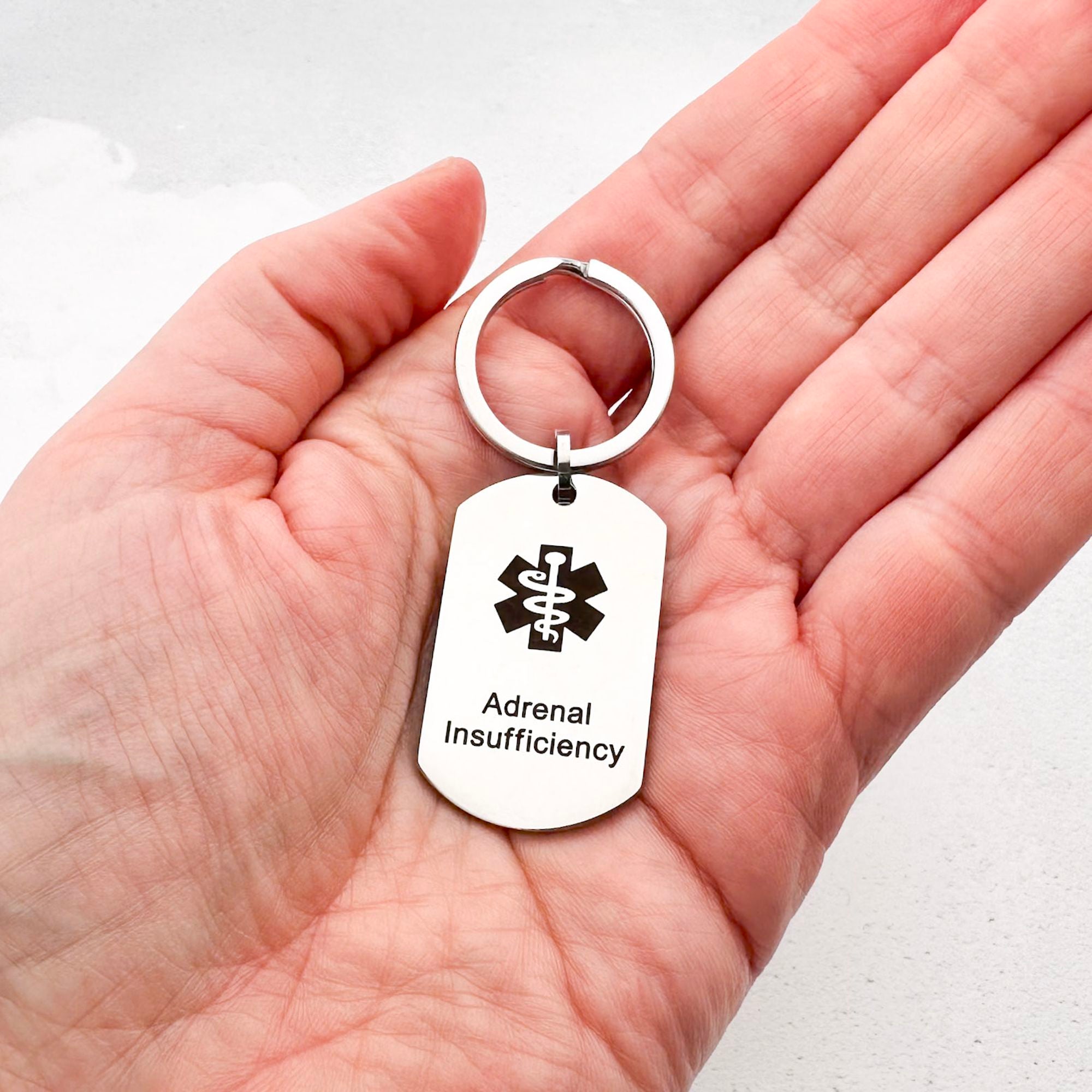stainless steel keychain with star of life medical symbol and 'Adrenal Insufficiency' text held in hand