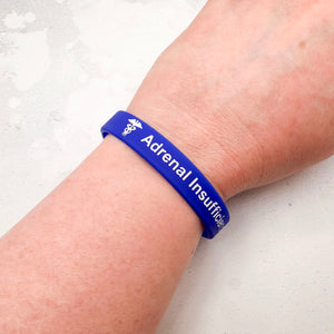 Blue silicone medical alert wristband worn on wrist for adrenal insufficiency