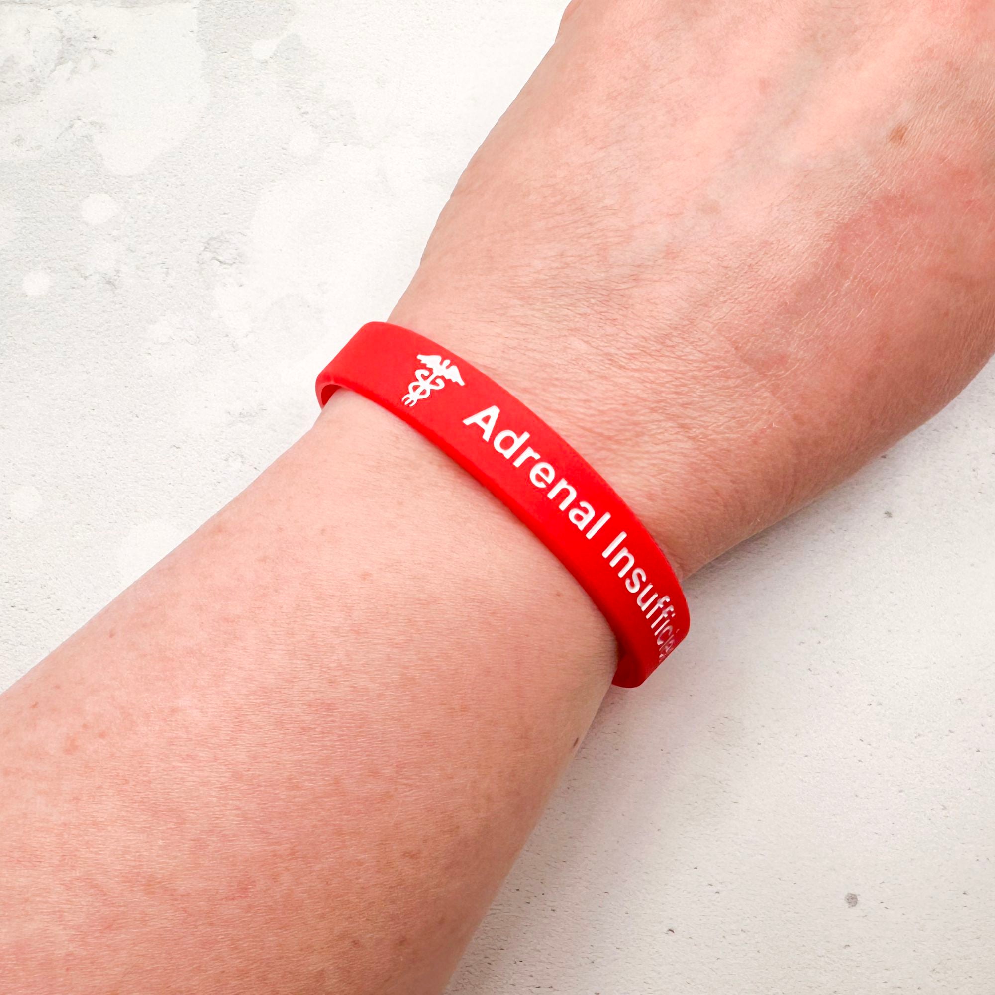 Red silicone adrenal insufficiency medical alert wristband worn on wrist