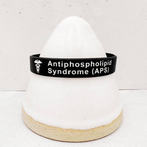 Close-up of an APS alert wristband showing clear medical identification text