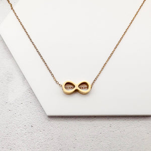 golden-tone stainless steel infinity slider charm on a chain necklace against a white background