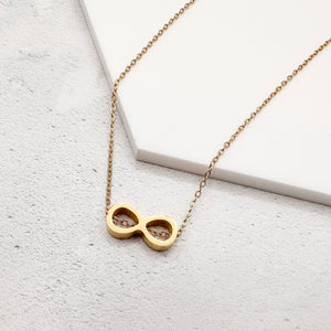 golden-tone stainless steel infinity slider charm on a chain necklace on a white surface