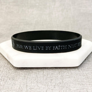 Black wristband with engraved text on a textured surface
