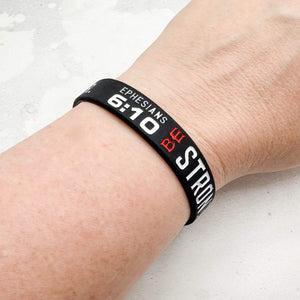 Black wristband with text on a person's wrist against a light background