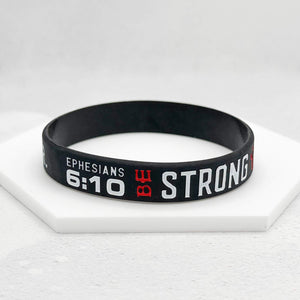 Black wristband with 'Be Strong' text on a white surface