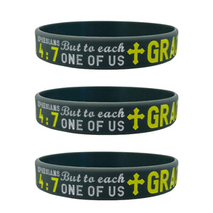 Three grey wristbands with yellow text and a cross symbol on a white background