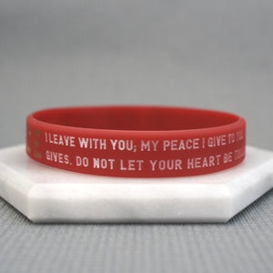 Red wristband with text on a white stand against a gray background