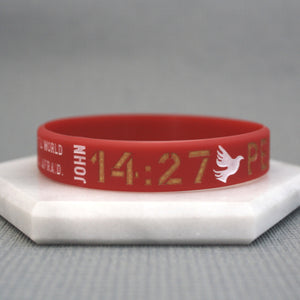Red wristband with text and a dove symbol on a gray background
