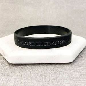 Black wristband with engraved text on a white stone surface