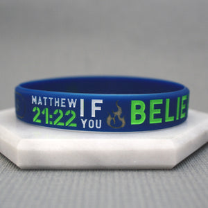 blue wristband with white and green text on a marble surface against a grey background