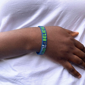 Hand wearing a blue wristband with text on a white background