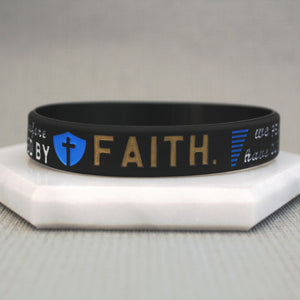 Black wristband with 'FAITH' printed on it, featuring a blue shield and cross symbol, on a light gray background.
