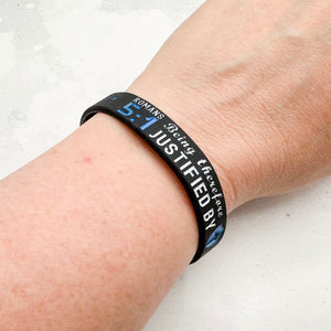 Black wristband with text on a person's wrist against a light background