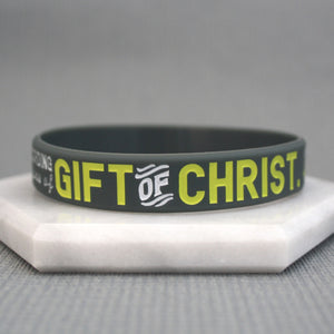 Grey wristband with yellow text 'GIFT OF CHRIST' on a gray background