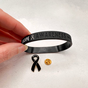 black silicone wristband engraved with ‘Hope & Awareness’ besides matching black enamel ribbon pin