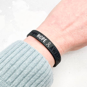 black silicone wristband engraved with ‘Hope & Awareness’ worn on person's wrist