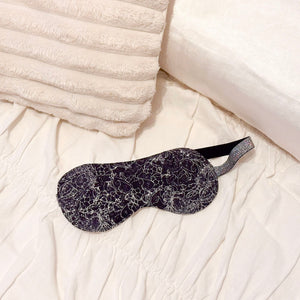 Black patterned sleep mask on a bed