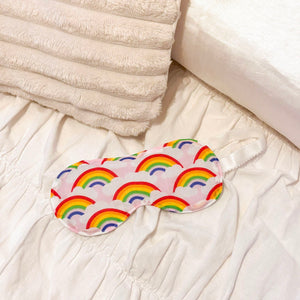 Sleep mask with rainbow pattern on a bed