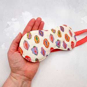 hand holding sleep mask with colourful female anatomy pattern 
