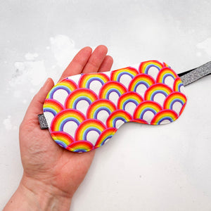 Hand holding a colourful rainbow-patterned eye mask