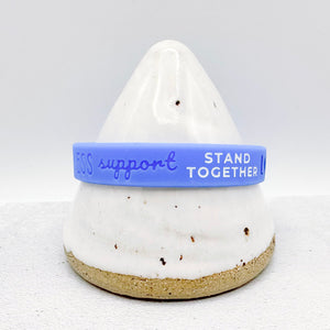 blue silicone awareness ribbon wristband with text engraved on its side 