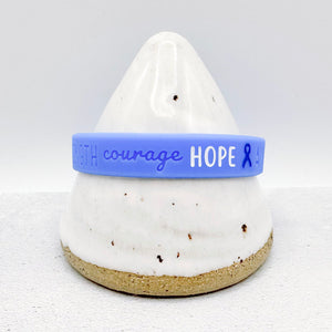 blue silicone awareness ribbon wristband with text engraved on its side 