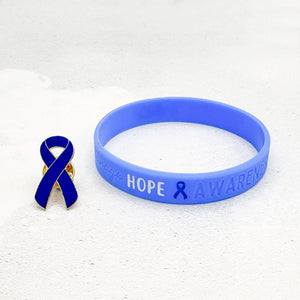 blue silicone awareness ribbon wristband with "Hope & Awareness" text engraved on its side, and a blue enamel ribbon pin besides it