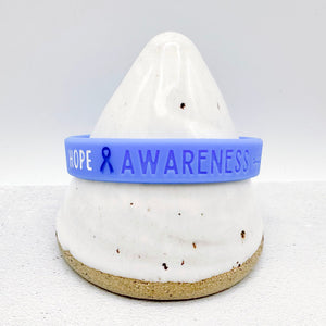 blue silicone awareness ribbon wristband with "Hope & Awareness" text engraved on its side 