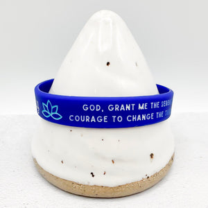 A blue silicone wristband with white text and a light blue lotus symbol