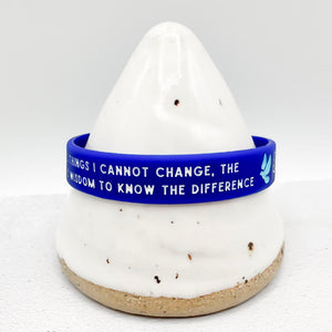 A blue silicone wristband with white text and a small light blue dove symbol