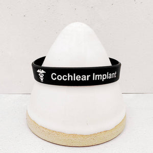 Close-up of a cochlear implant wristband showing clear medical identification text