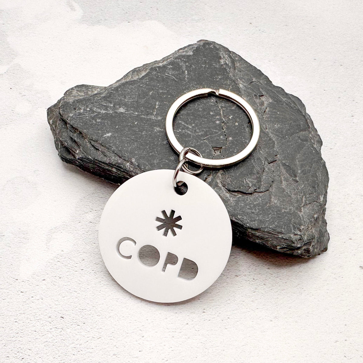 lightweight white acrylic round keychain with 'COPD' laser cut out