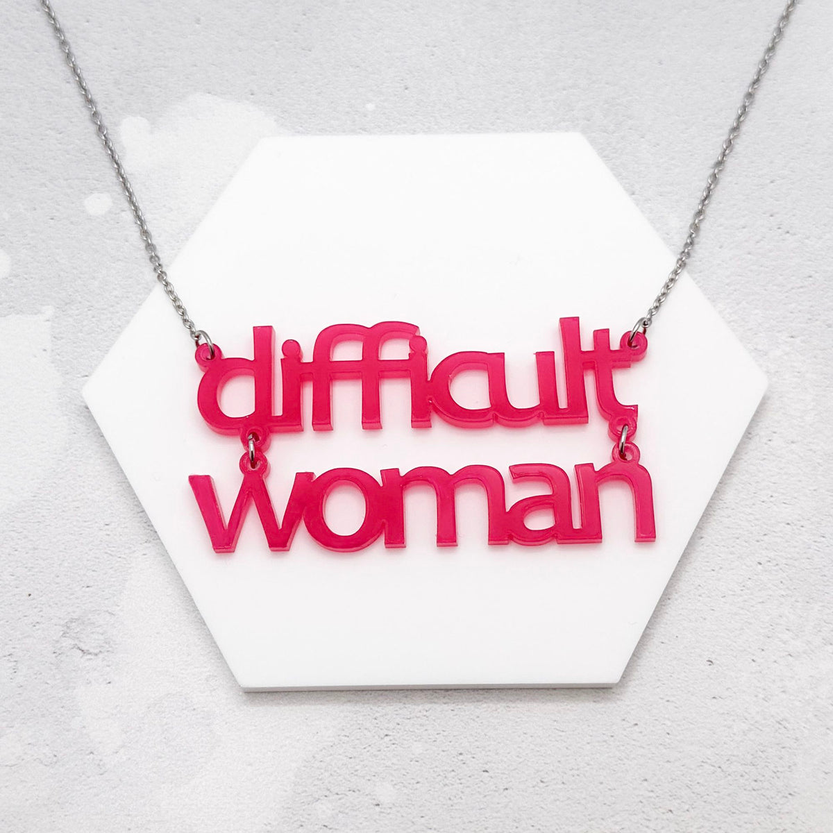 hot pink acrylic necklace which reads 'difficult woman' on a stainless steel chain