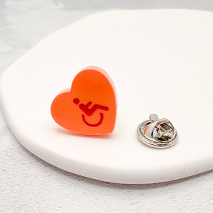 orange acrylic heart pin with disabled symbol in red