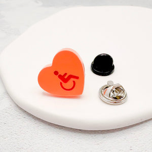 orange acrylic heart pin with disabled symbol in red, with rubber backing option