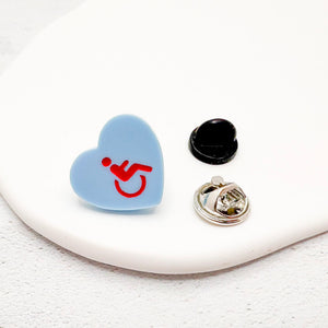 blue acrylic heart pin with disabled symbol in red, with rubber backing option