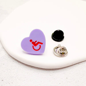 Purple acrylic heart pin with disabled symbol in red, with rubber backing option
