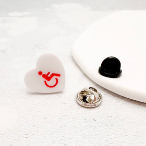 white acrylic heart pin with disabled symbol in red, with rubber backing option