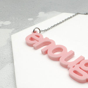 Close-up of laser-cut “enough” acrylic pendant on silver chain