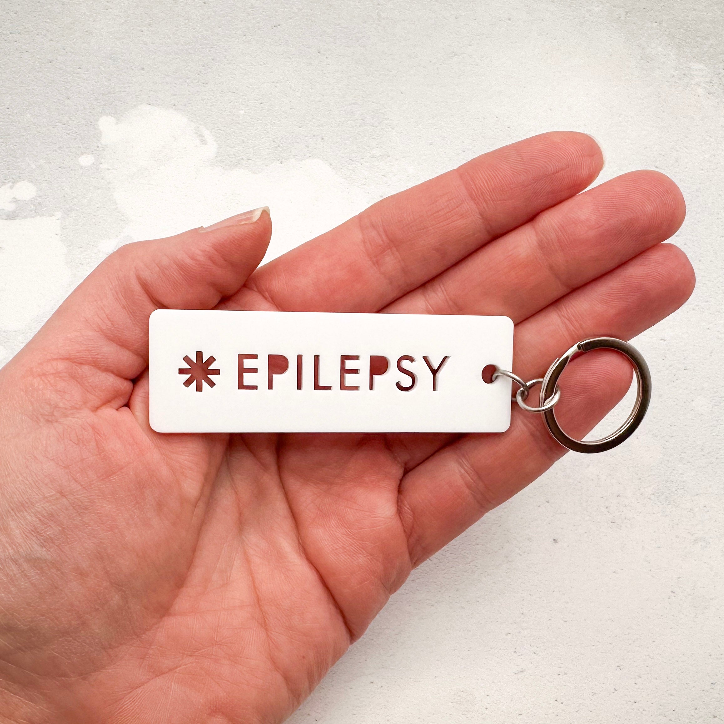 Acrylic epilepsy medical alert keychain with laser-cut text and silver keyring held in hand
