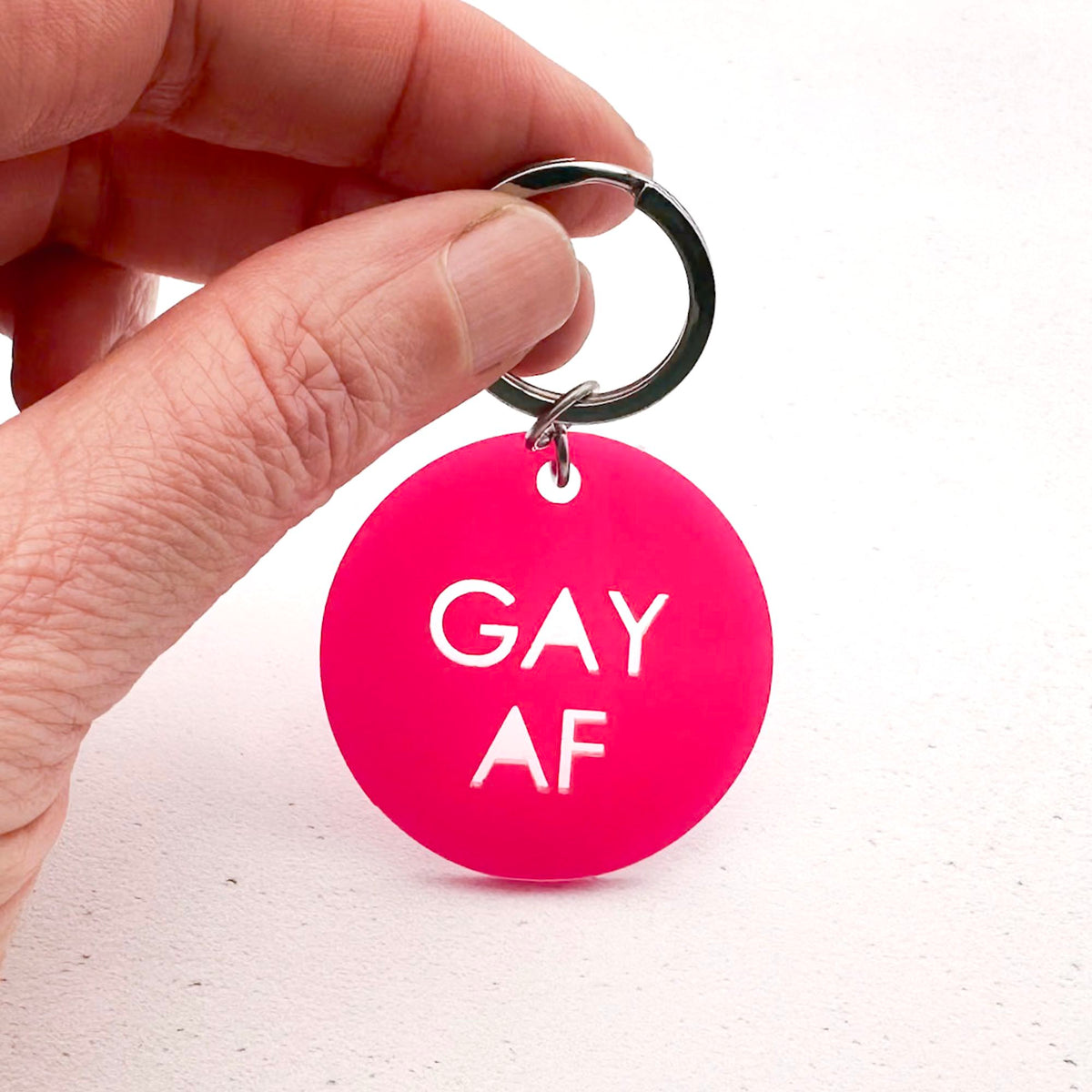 round hot pink acrylic keychain with "GAY AF" text