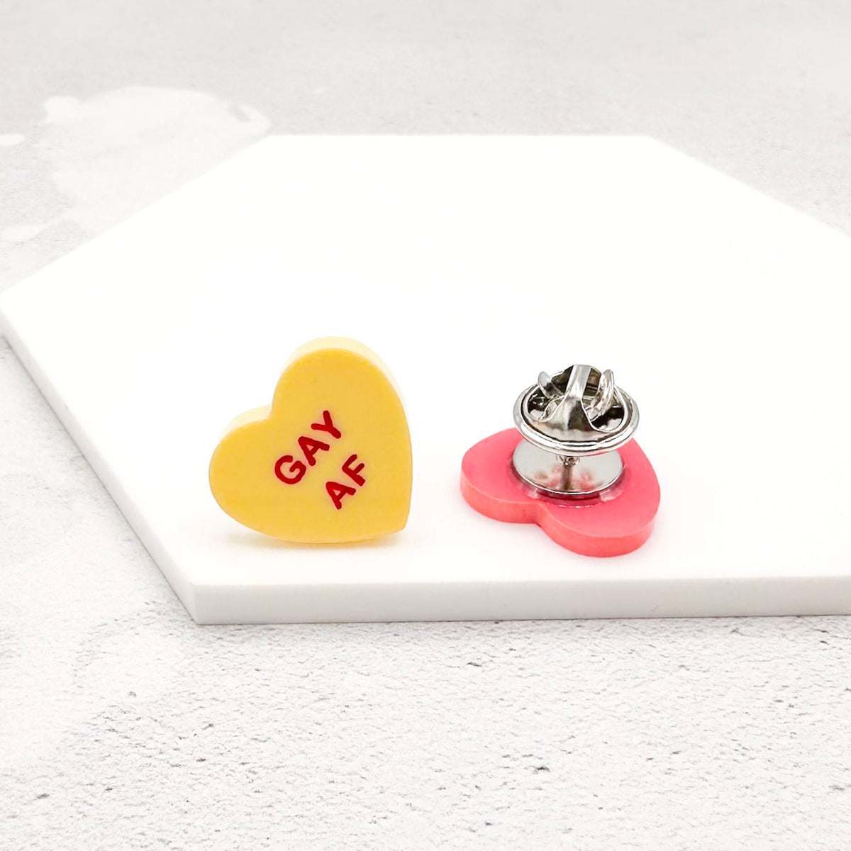yellow acrylic heart pin with "Gay AF" hand-painted in red
