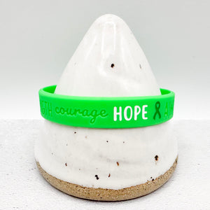 green awareness ribbon wristband with "courage & hope" text engraved on the side