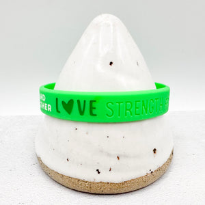 green awareness ribbon wristband with "love strength" text engraved on the side