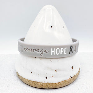 grey awareness ribbon wristband with "courage hope" text engraved on its side 