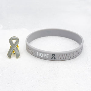 grey awareness ribbon wristband with "hope & awareness" text engraved on its side and a matching grey enamel ribbon pin next to it